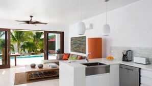 Une cuisine moderne dotée d’un îlot central, d’un lave-vaisselle intégré et offrant une vue sur une piscine.