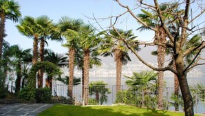 Ein angelegter Garten mit Palmen, einem Kiesweg und Blick auf ein Gewässer.