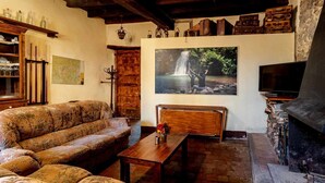 A cozy living room with a patterned sofa, a wooden coffee table, a fireplace, and a large wall-mounted TV. - Can Ventura - relaxation in nature (Sant Feliu De Pallerols)