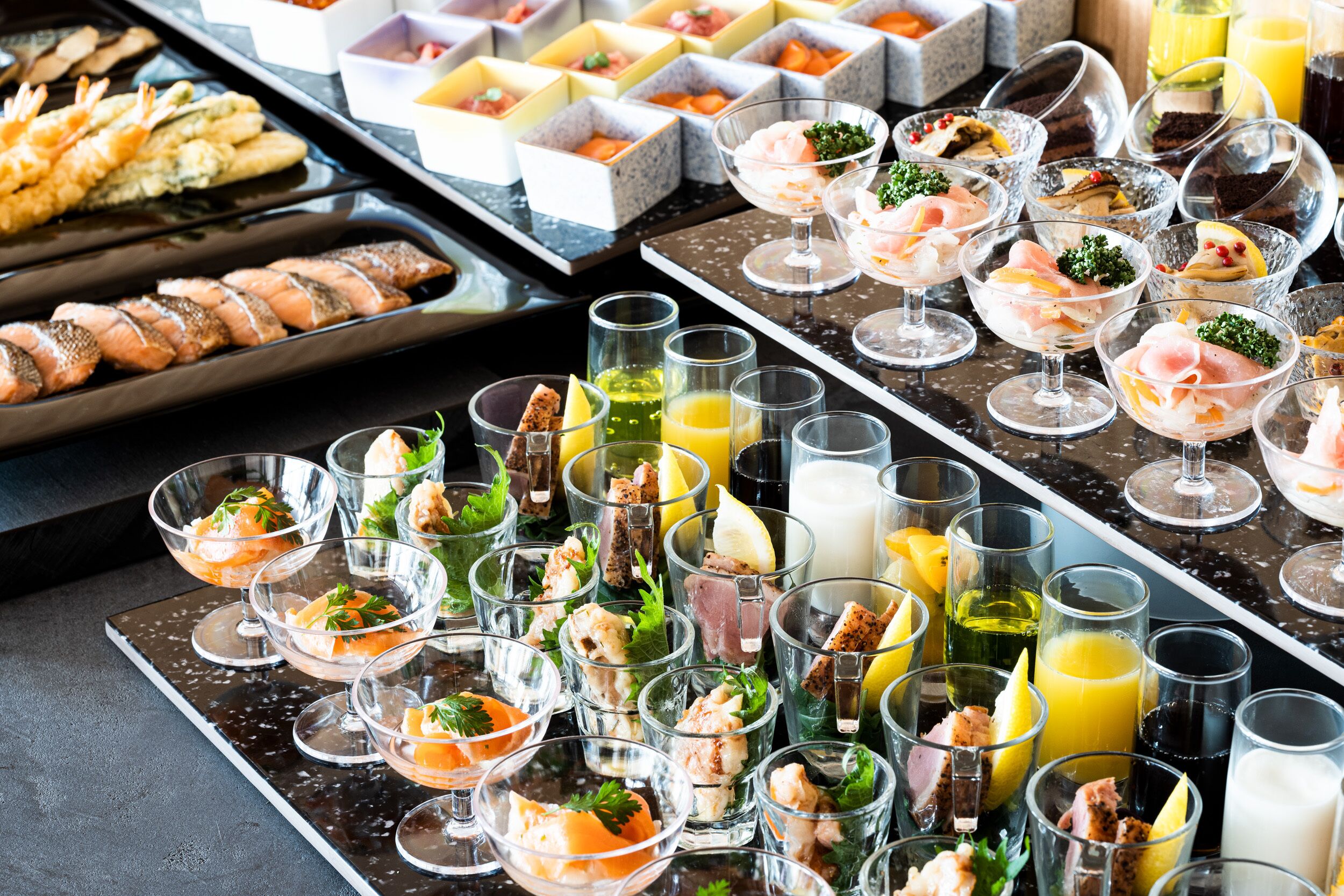 Un bufé con diversos platos de mariscos, como camarones y salmón, y una selección de bebidas.