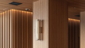 A modern interior with a wooden panel wall, recessed ceiling lights, and a sectional sofa with cushions. - Bespoke Hotel Sapporo (Sapporo)