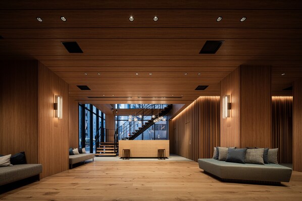 Un vestíbulo amplio con piso de madera, un mostrador de recepción y una escalera que conduce a los pisos superiores.