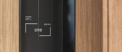 A modern elevator with a minimalist design, featuring a reception area and a sign indicating the elevator's direction.