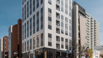 A modern multi-story hotel with a prominent 'BSKP' sign, featuring a clean, white facade and numerous windows.