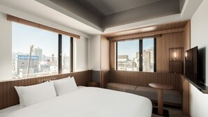 A modern hotel room with a large bed, a seating area, a TV, and a city view. - Bespoke Hotel Sapporo (Sapporo)