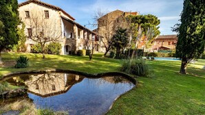 A courtyard with a pond, stone buildings, and a pool area.