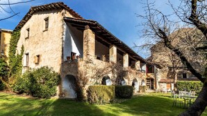 A rustic building with a courtyard, stone arches, and a tiled roof.