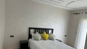 A bedroom with a bed, two bedside tables, and a window with curtains.