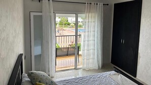 A bedroom with a bed, a wardrobe, and a sliding glass door leading to a balcony.