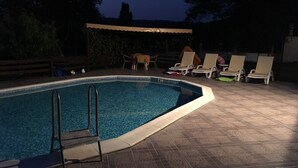 An outdoor swimming pool with a tiled deck, lounge chairs, and a covered seating area. - Inviting 4-Bed Villa in Dolishte (Varna)