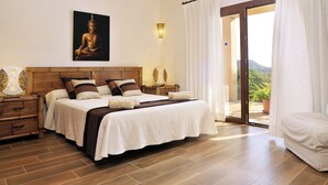 A bedroom with a large bed, wooden headboard, and a Buddha painting. There is a nightstand with a lamp and a potted plant. - Finca Mimosa - haven of peace with amazing views (Cala D'or)
