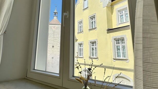 A window with a view of yellow buildings and a clear sky.