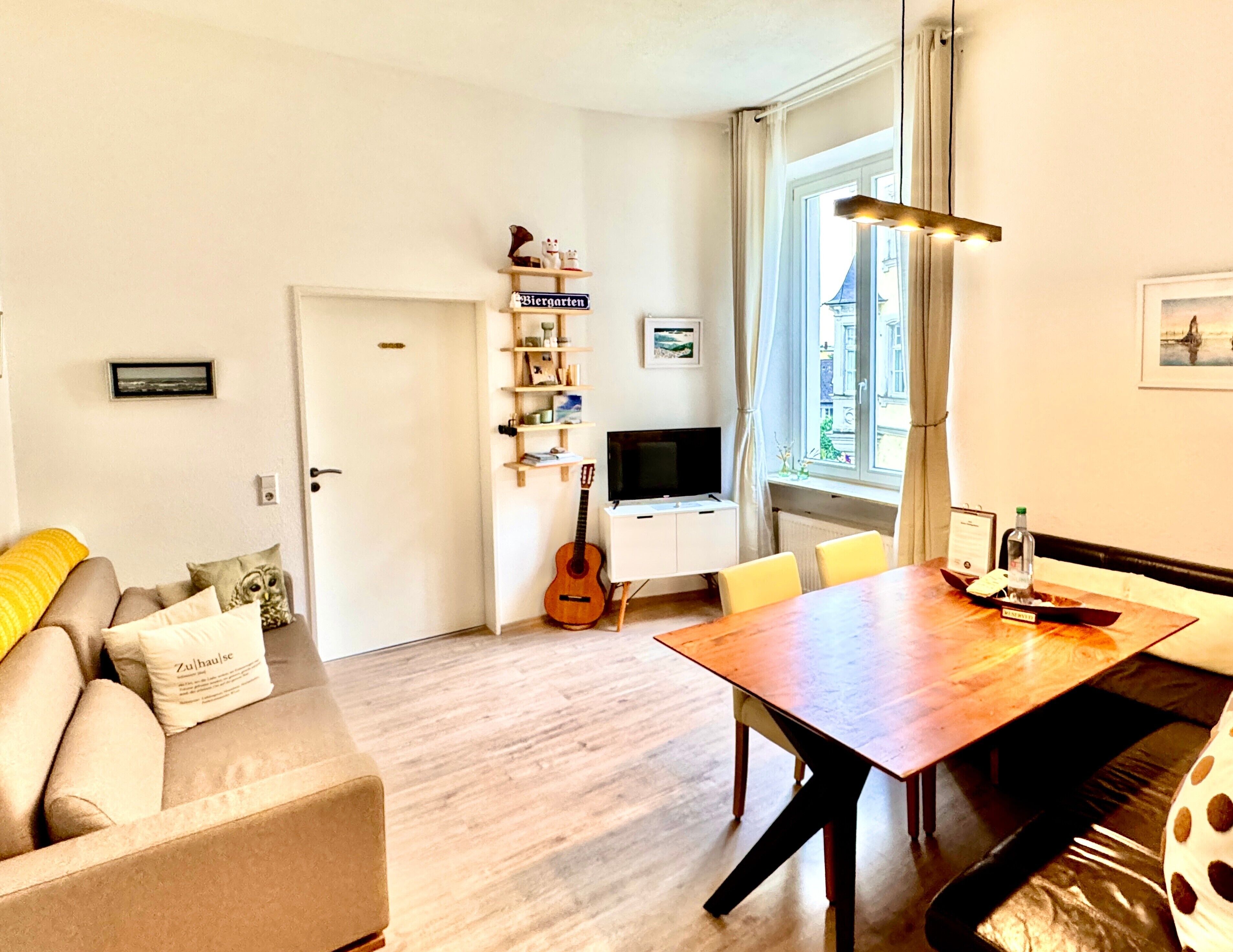 Un salon avec un canapé, une table à manger, une guitare et un téléviseur.