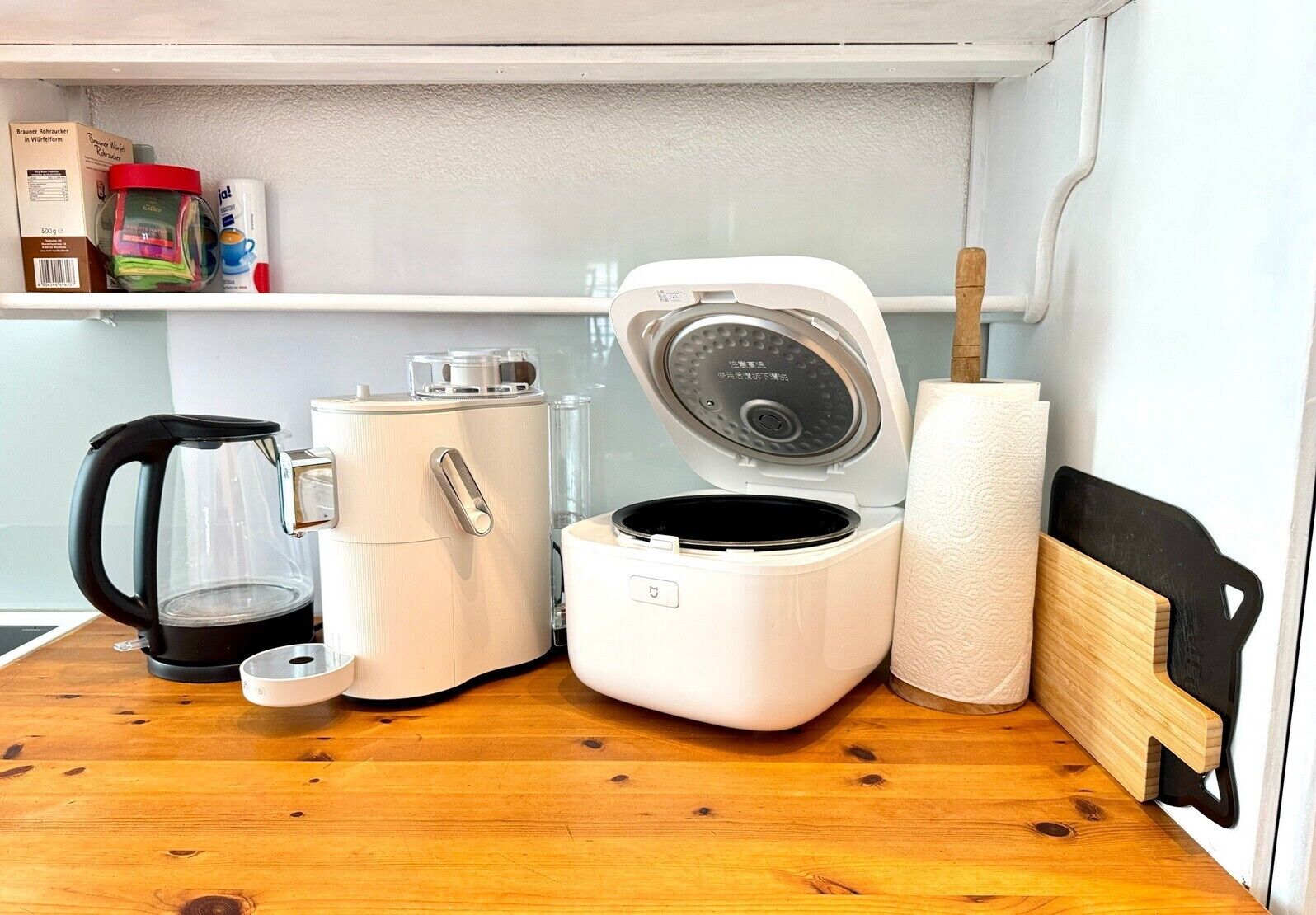 A compact kitchenette with a coffee maker, a rice cooker, and a paper towel holder.
