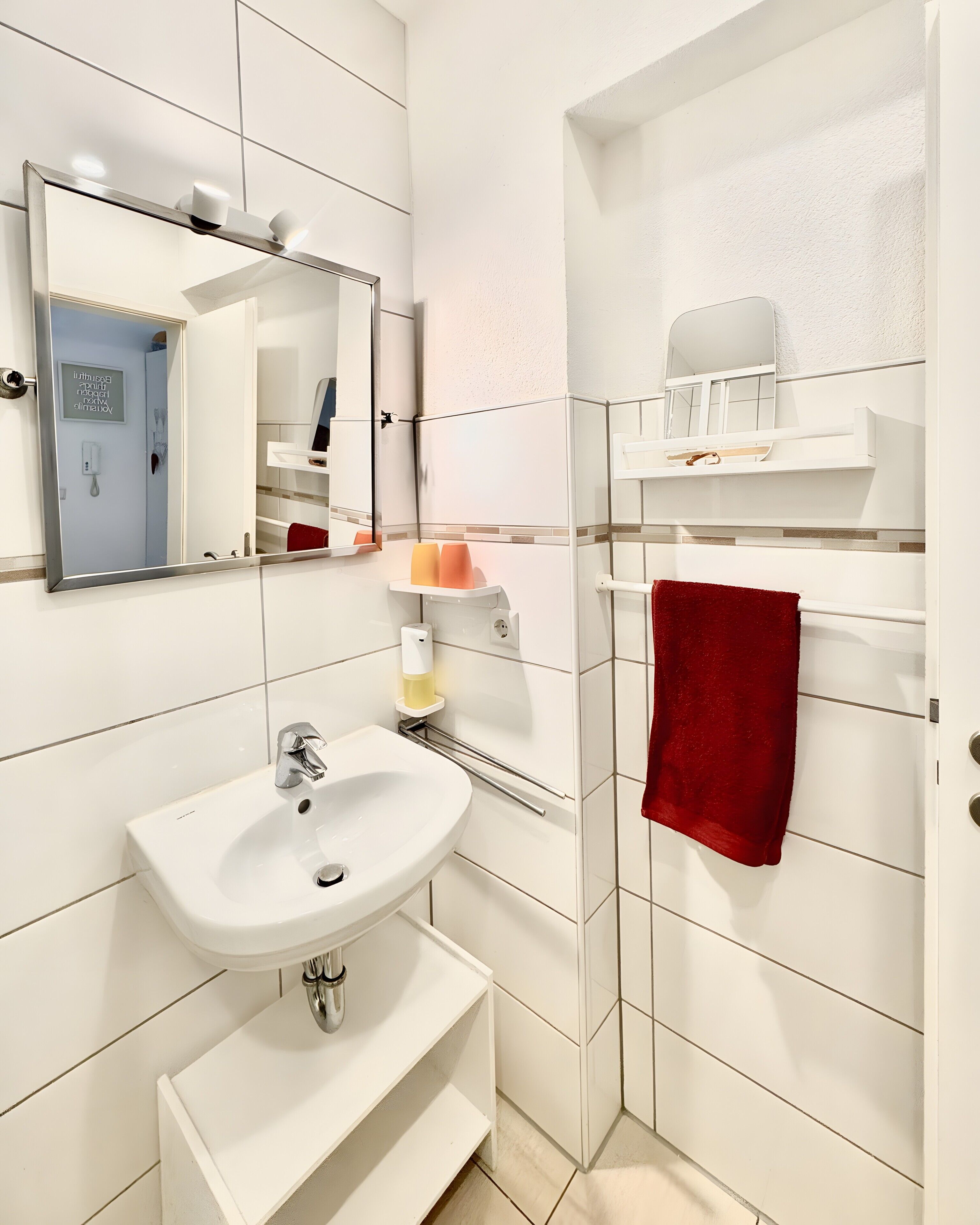 A modern bathroom with a white sink, mirror, and towel rack.