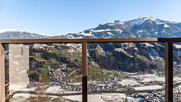 A panoramic view of a mountainous town with snow-covered peaks, a river, and a town layout including buildings and roads.