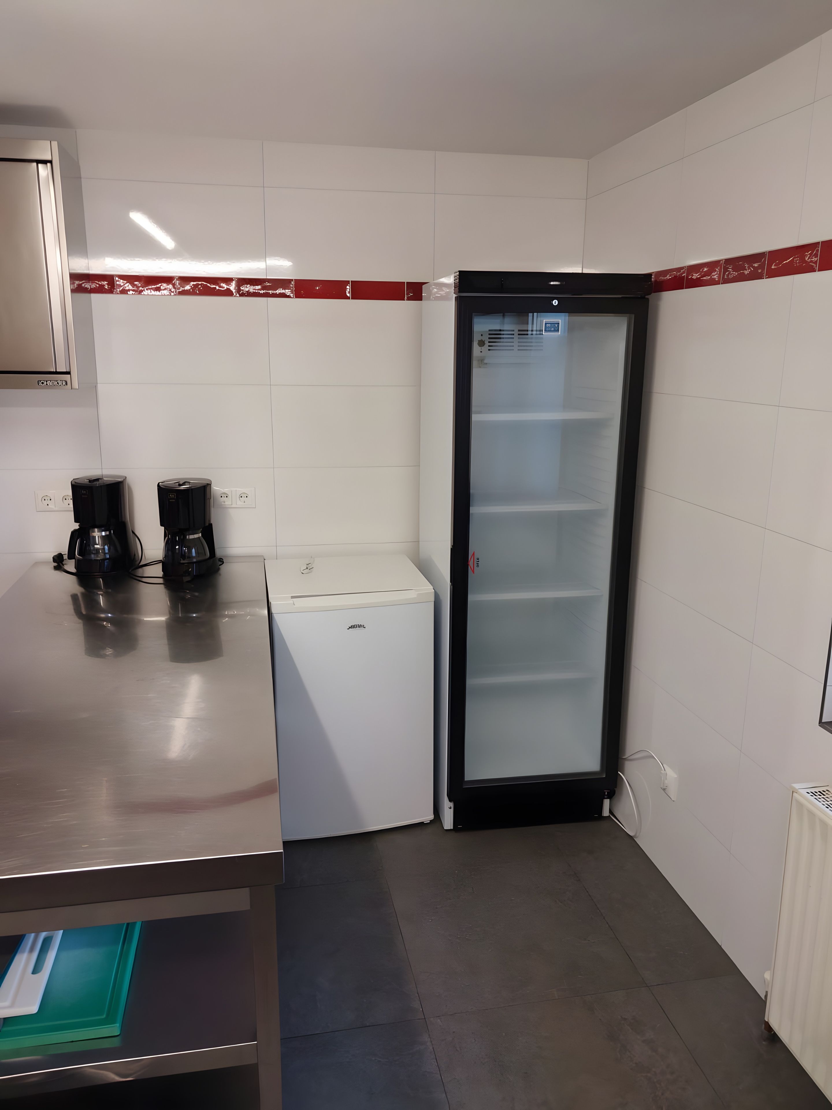 Pieni keittiönurkkaus, jossa on kahvinkeitin, minijääkaappi ja mikroaaltouuni.