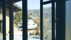 A view through a window with a frosted glass design, revealing a street scene with buildings and a clear sky. - Kominka yado LOOF Kyo no ie (Hokuto)