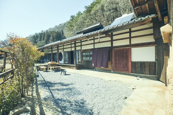 Un edificio japonés tradicional con patio de grava, vigas de madera y techo de paja.