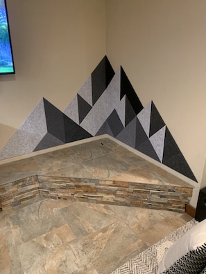 Unique geometric pattern adorns the wall, complemented by a fireplace and neutral-toned tile flooring.