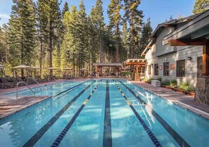 Swimmers can enjoy a competitive pool experience surrounded by tall pine trees and a nearby lodge.