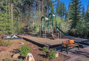 Explore a lush play area with a climbing structure, slide, and scenic views.