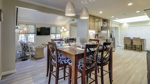 A spacious dining area with a wooden table set for four, surrounded by chairs with patterned cushions. - Sunset Rentals | Lawton 45 | Dog Friendly | (Hilton Head Island)