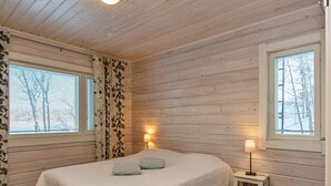 Et soveværelse med en seng, to sengeborde med lamper og et vindue med gardiner.