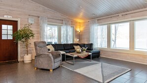 En rummelig stue med sofasæt, sofabord og en potteplante.