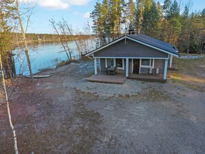 Une cabane dotée d’une terrasse, d’un porche couvert et offrant une vue sur un lac.
