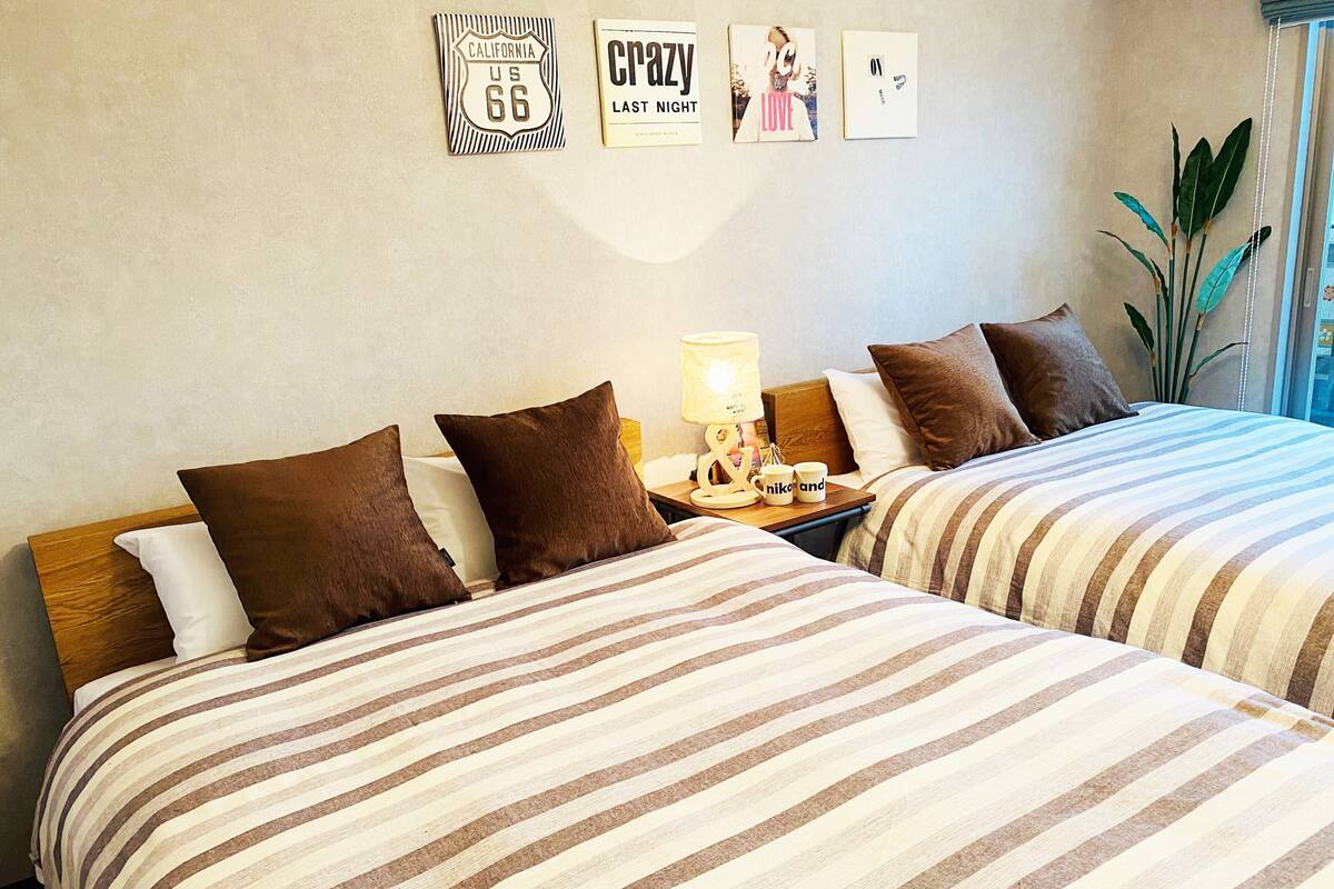 Une chambre d’hôtel avec deux lits, une literie à rayures, une table de chevet avec une lampe et des œuvres d’art mural.