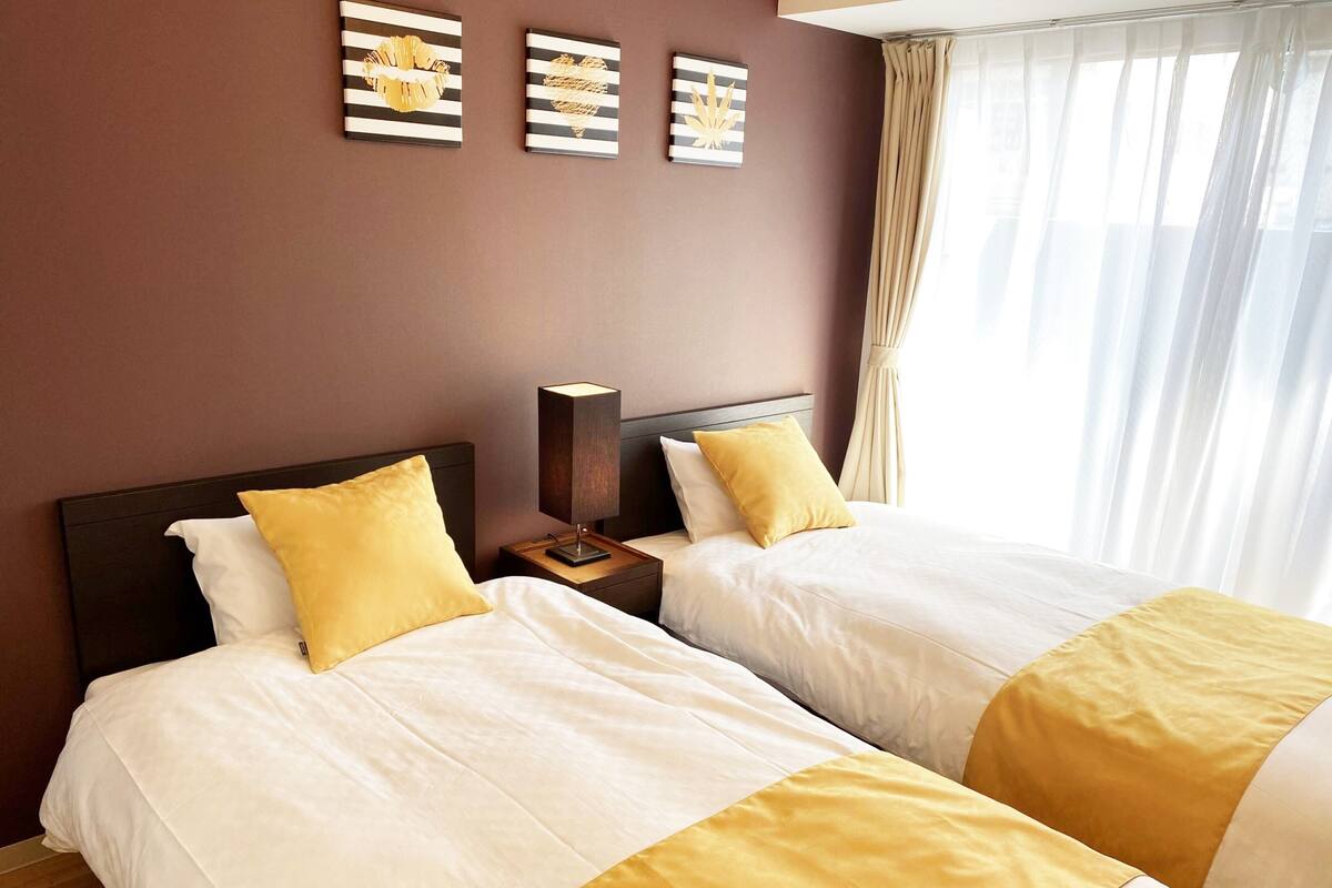 Une chambre d’hôtel avec deux lits, une table de chevet avec une lampe et des œuvres d’art accrochées au mur.