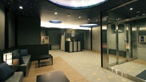 Een moderne lobby met een receptiebalie, zithoek en lift.
