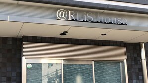 De buitenkant van @RLiS house met een modern ontwerp, met een groot raam en een metalen luifel boven de ingang.