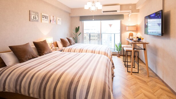 Een hotelkamer met twee bedden, een klein tafeltje met stoelen, een televisie en een balkon met uitzicht.