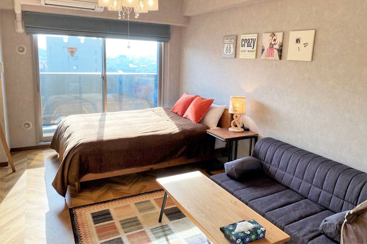 Une chambre moderne avec un lit, un canapé, une petite table et une fenêtre donnant sur un beau paysage.