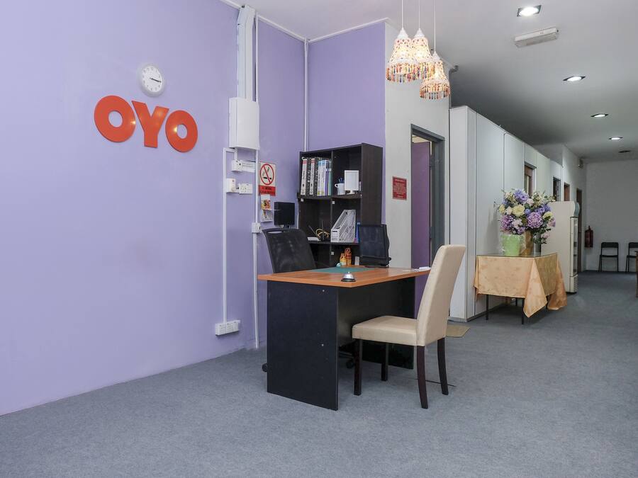 A reception area with a desk, chairs, a clock, and a 'OYO' sign on the wall.