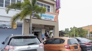 Um edifício com a placa UMAIRA ENTERPRISE, uma concessionária de carros e carros estacionados na frente.