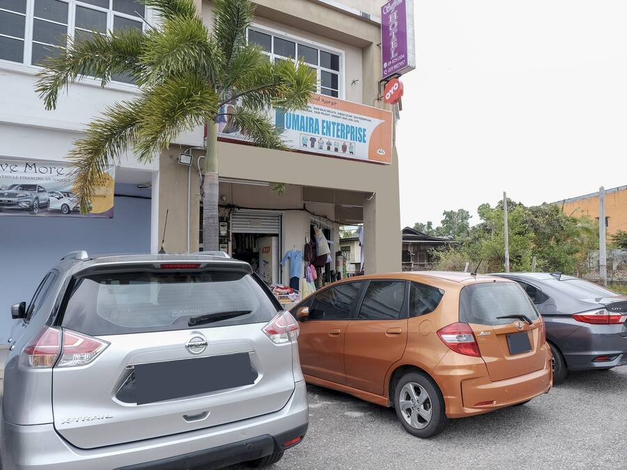 Un bâtiment portant une enseigne indiquant « UMAIRA ENTERPRISE », un concessionnaire automobile, avec des voitures garées devant.