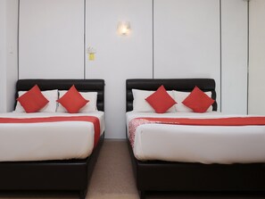 Two beds with black headboards and red pillows, white bedding, and a small wall-mounted light fixture. - OYO 90180 Gemilang Hotel Kerteh (Kerteh)
