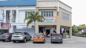 Um edifício com uma placa da Jumaira Enterprise, um estacionamento com vários carros e uma palmeira em frente.