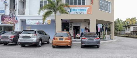 Un edificio con il cartello di Jumaira Enterprise, un parcheggio con diverse auto e una palma davanti.