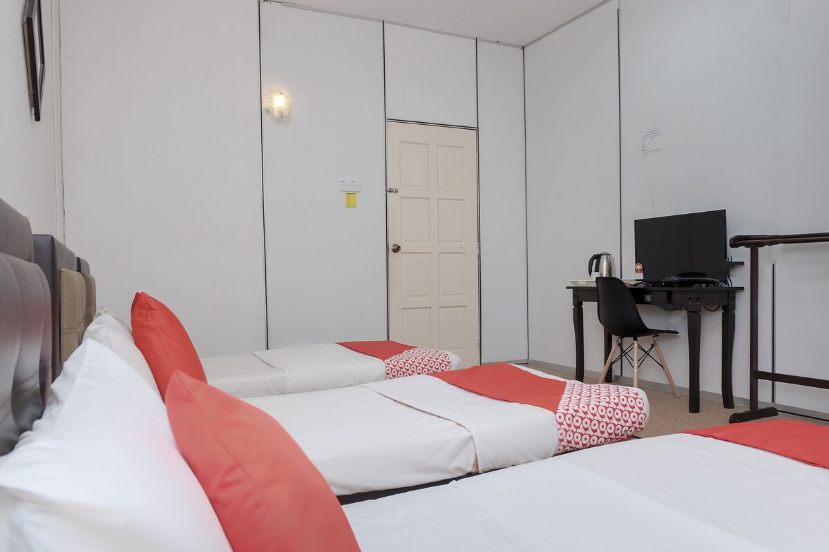 A hotel room with two beds, a desk with a television, and a chair.