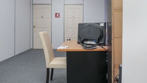 Uma sala de conferências com uma mesa, uma cadeira, um ventilador de teto e duas portas.