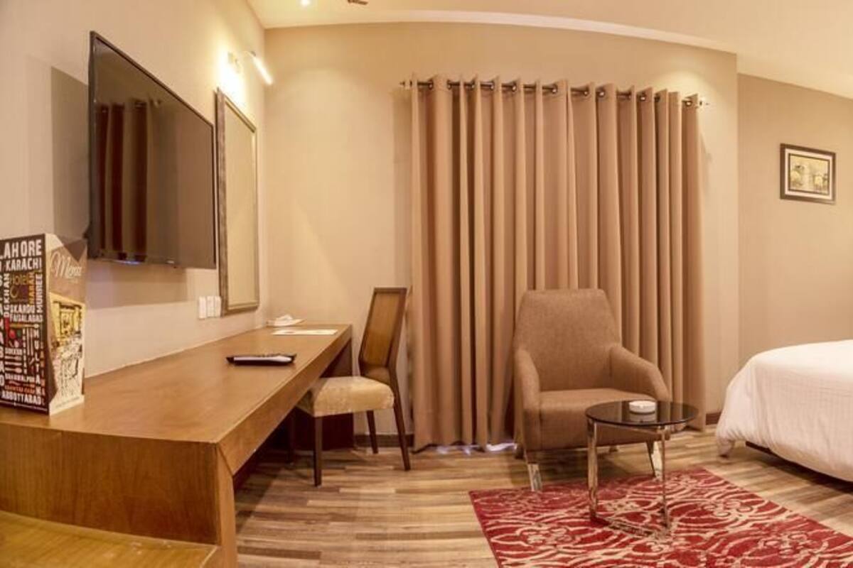 Une chambre d’hôtel avec un grand lit, un bureau avec une chaise, une petite table et un miroir.