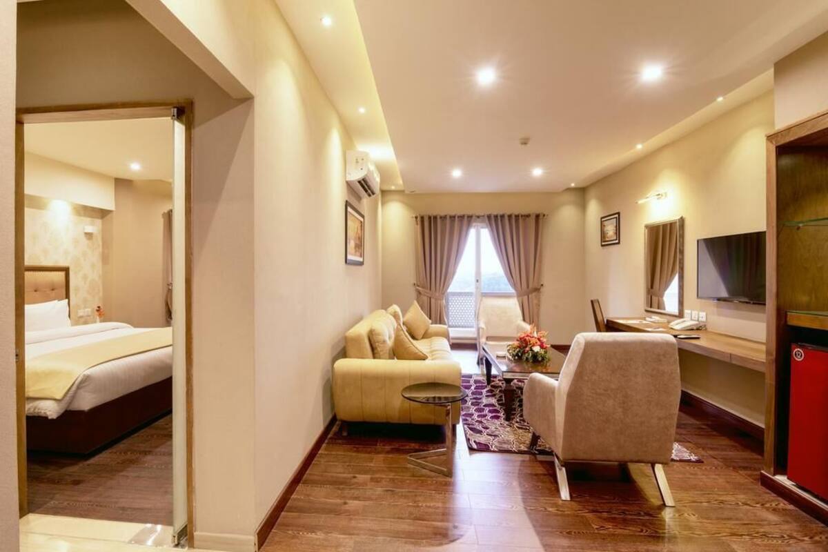 Une chambre d’hôtel avec un lit, un canapé, un bureau, une chaise et un téléviseur.