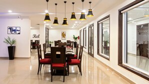Un comedor moderno con una mesa larga, sillas rojas e iluminación colgante negra.
