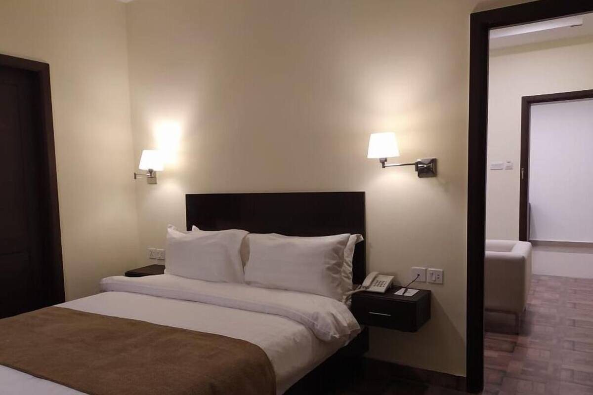 A hotel room with a bed, bedside lamps, a telephone, and a nightstand.