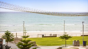 A beachside patio with a view of the ocean, outdoor seating, and a grassy area. - Ramsgate Hotel by Nightcap Social (Henley Beach)