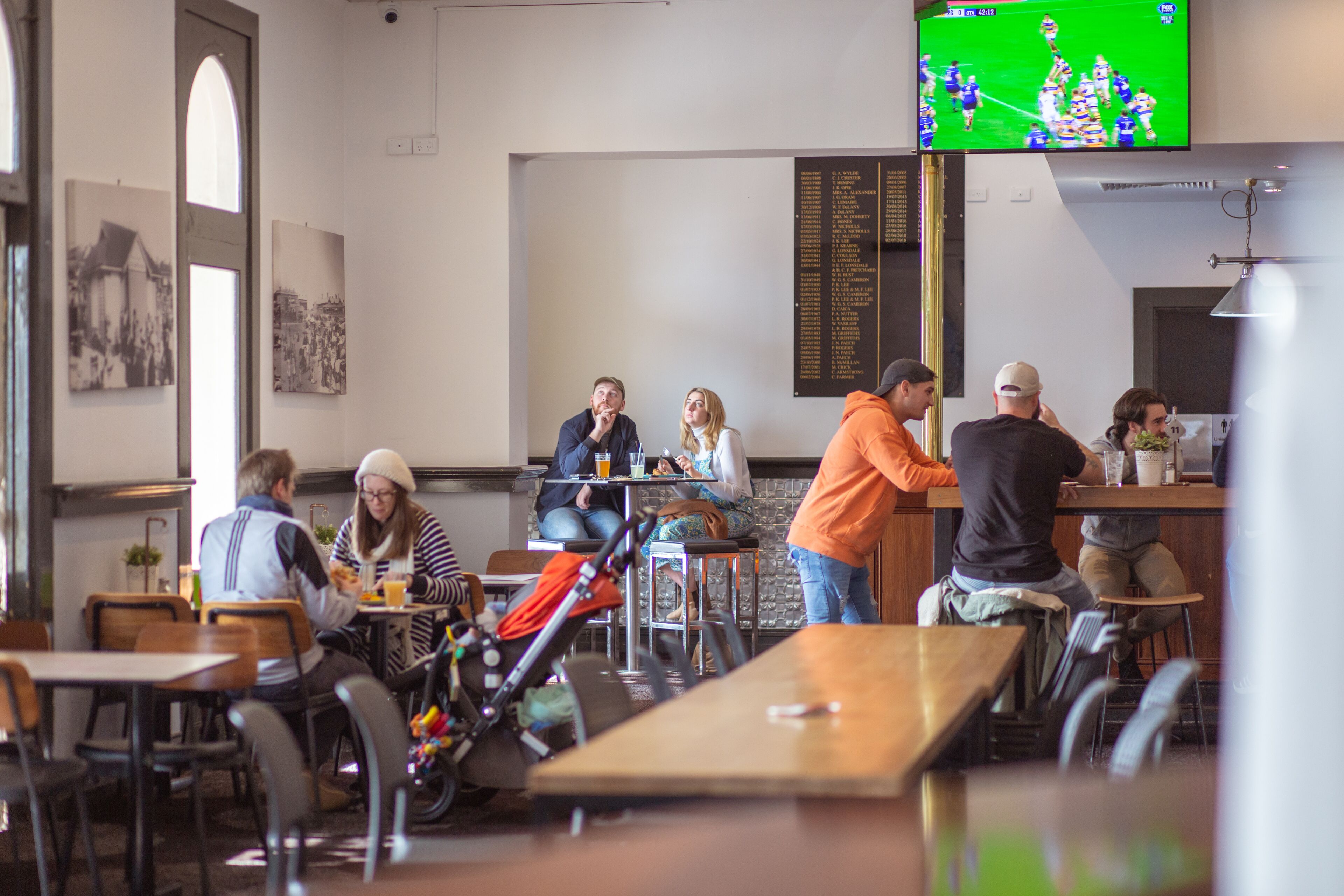 A restaurant with tables and chairs, a counter, and a television mounted on the wall.